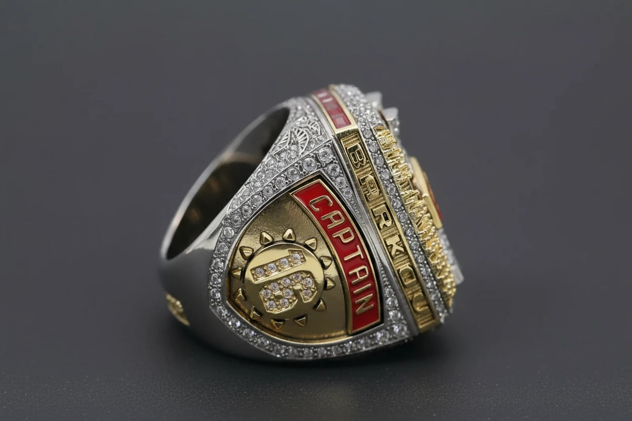 Gold and silver ring with 'Captain' inscription on a dark background